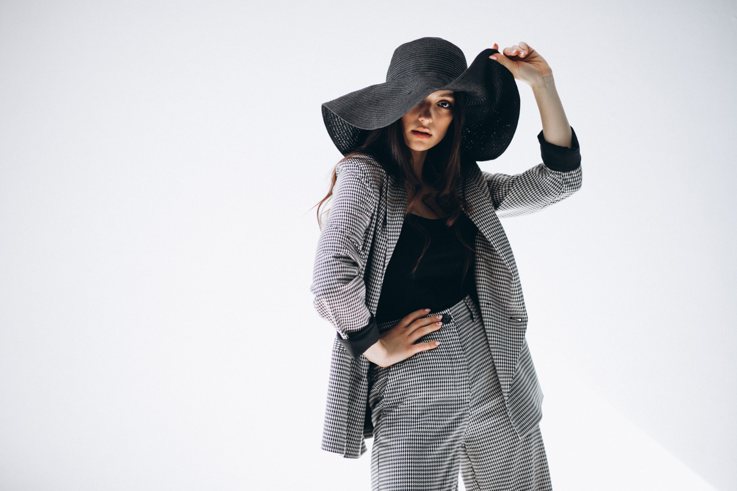 Young woman in a business suit wearing a hat in studio